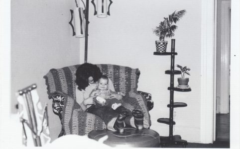 a black and white photo of me as a baby on my mom's lap. she is looking at me and smiling, and I am laughing.