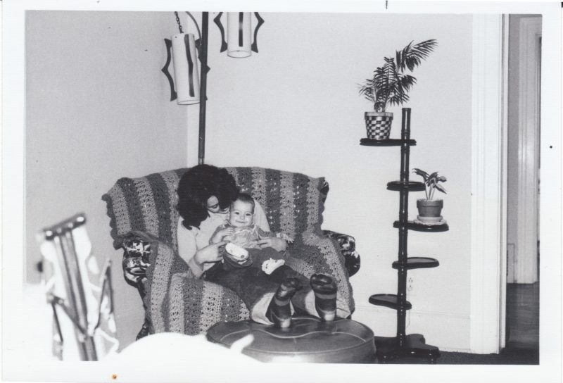 a black and white photo of me as a baby on my mom's lap. she is looking at me and smiling, and I am laughing.