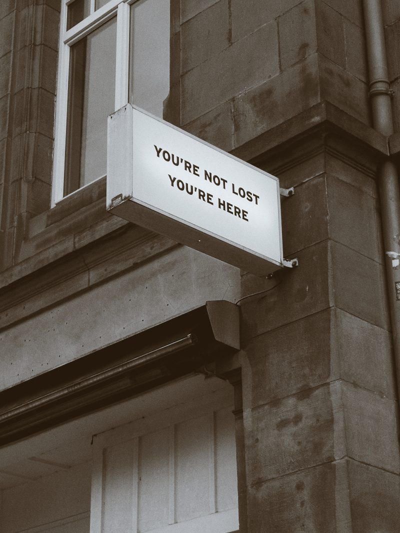 a sign on a building reads 'YOU'RE NOT LOST, YOU'RE HERE'