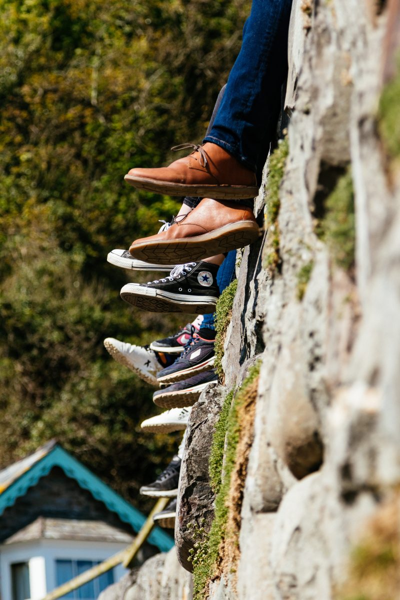 tilt-shift view of feet in sneakers, presumably belonging to people sitting atop a stone wall