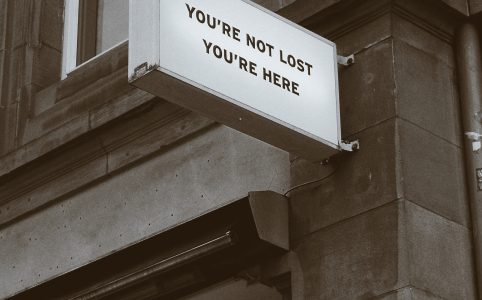 a sign on a building reads 'YOU'RE NOT LOST, YOU'RE HERE'