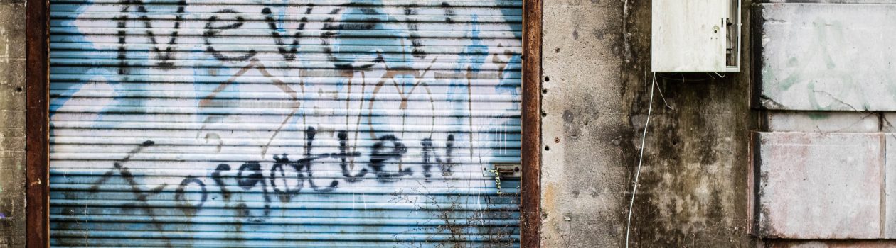 'never forgotten' spray painted on an old metal door