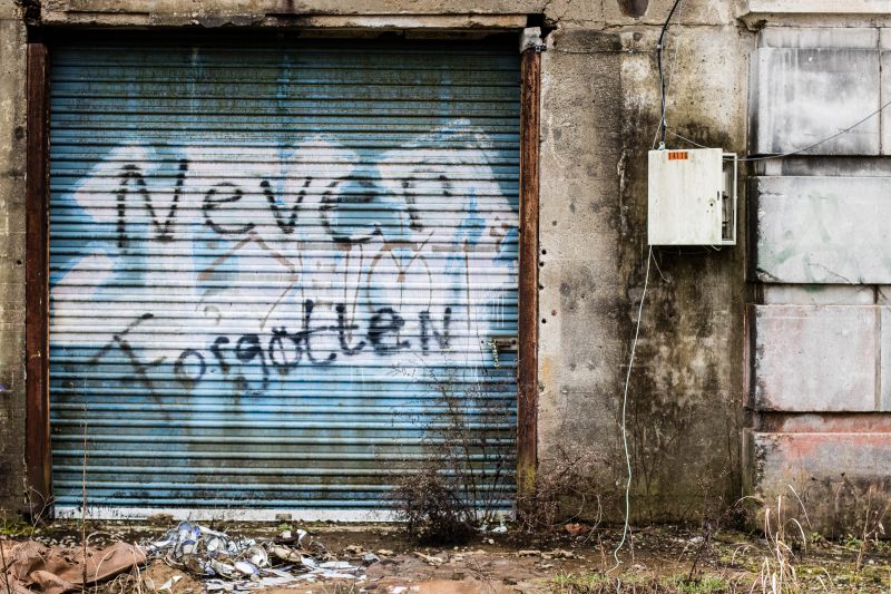'never forgotten' spray painted on an old metal door