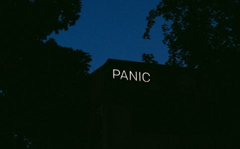 a neon sign reading PANIC on the side of a building in the dark