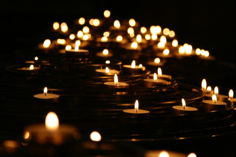 a photo of many lit candles in the dark
