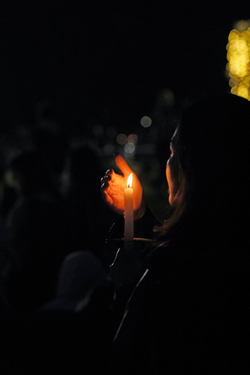 a person shields a candle's flame with their hand in the dark