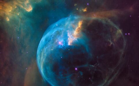 a photo of a blue and gold area of space with a bubble shaped nebula cloud, taken by NASA.