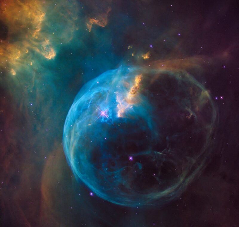 a photo of a blue and gold area of space with a bubble shaped nebula cloud, taken by NASA.