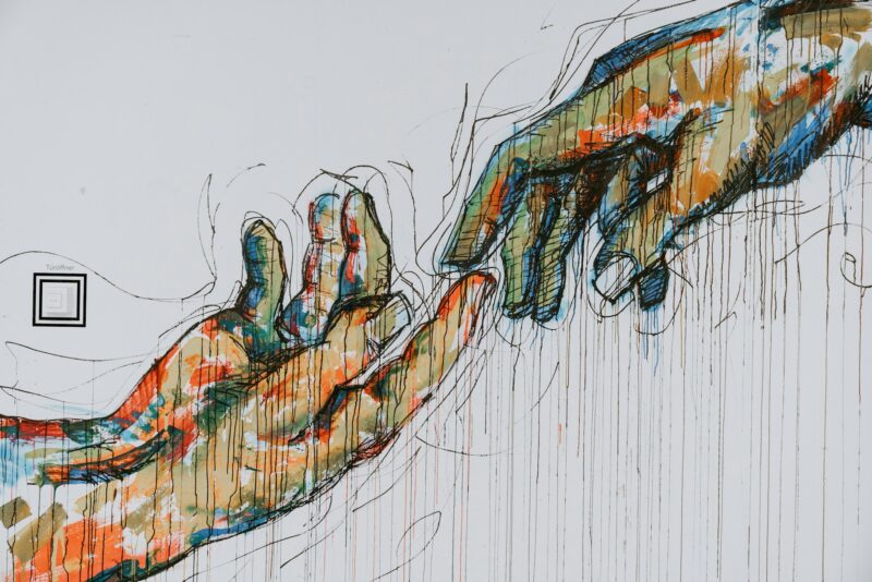 a large painting of multicolored hands reaching toward each other.