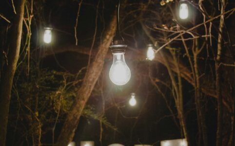 large letters made of lights that spell "HOPE" against a backdrop of trees and hanging lights at night